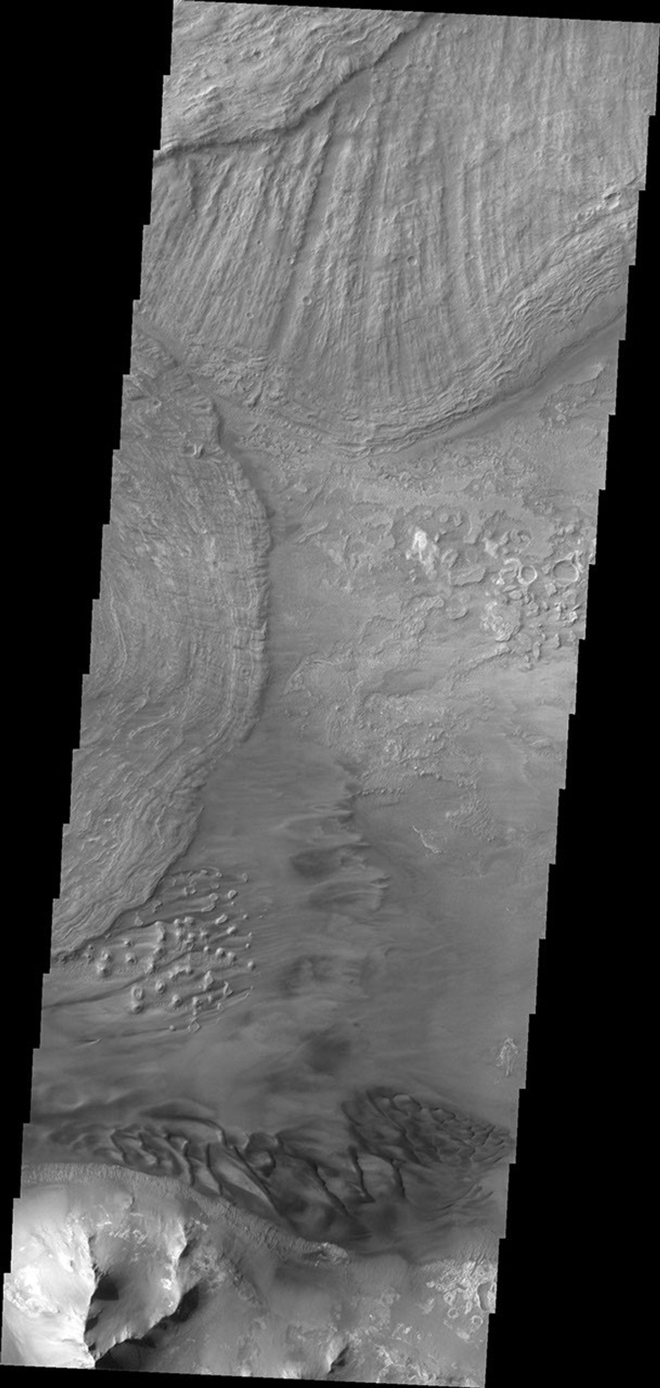 This image captured by NASA's 2001 Mars Odyssey spacecraft shows the eastern end of Ius Chasma. The southern canyon wall is at the bottom of the image, with dark sand and sand dunes.