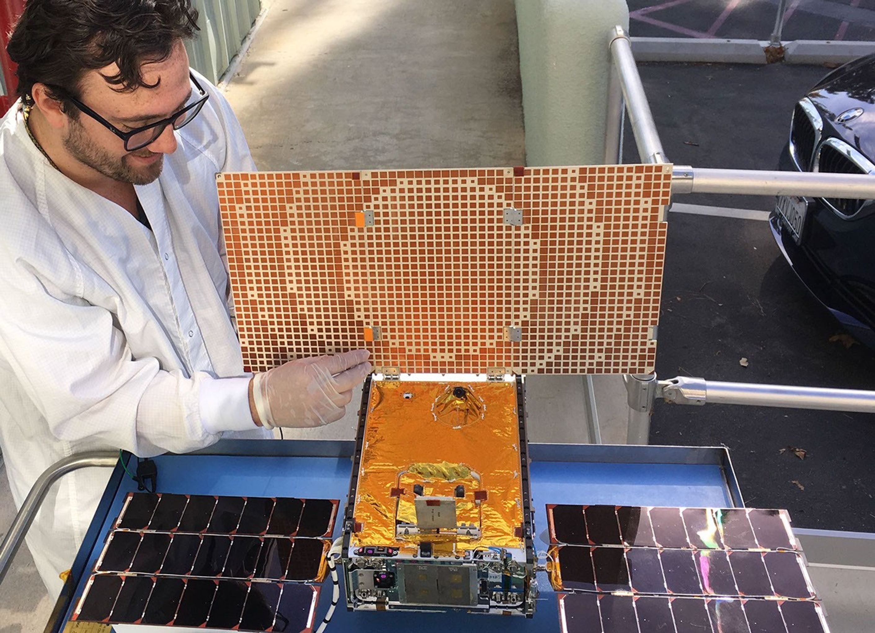 Engineer Joel Steinkraus uses sunlight to test the solar arrays on one of the Mars Cube One (MarCO) spacecraft at NASA's Jet Propulsion Laboratory.