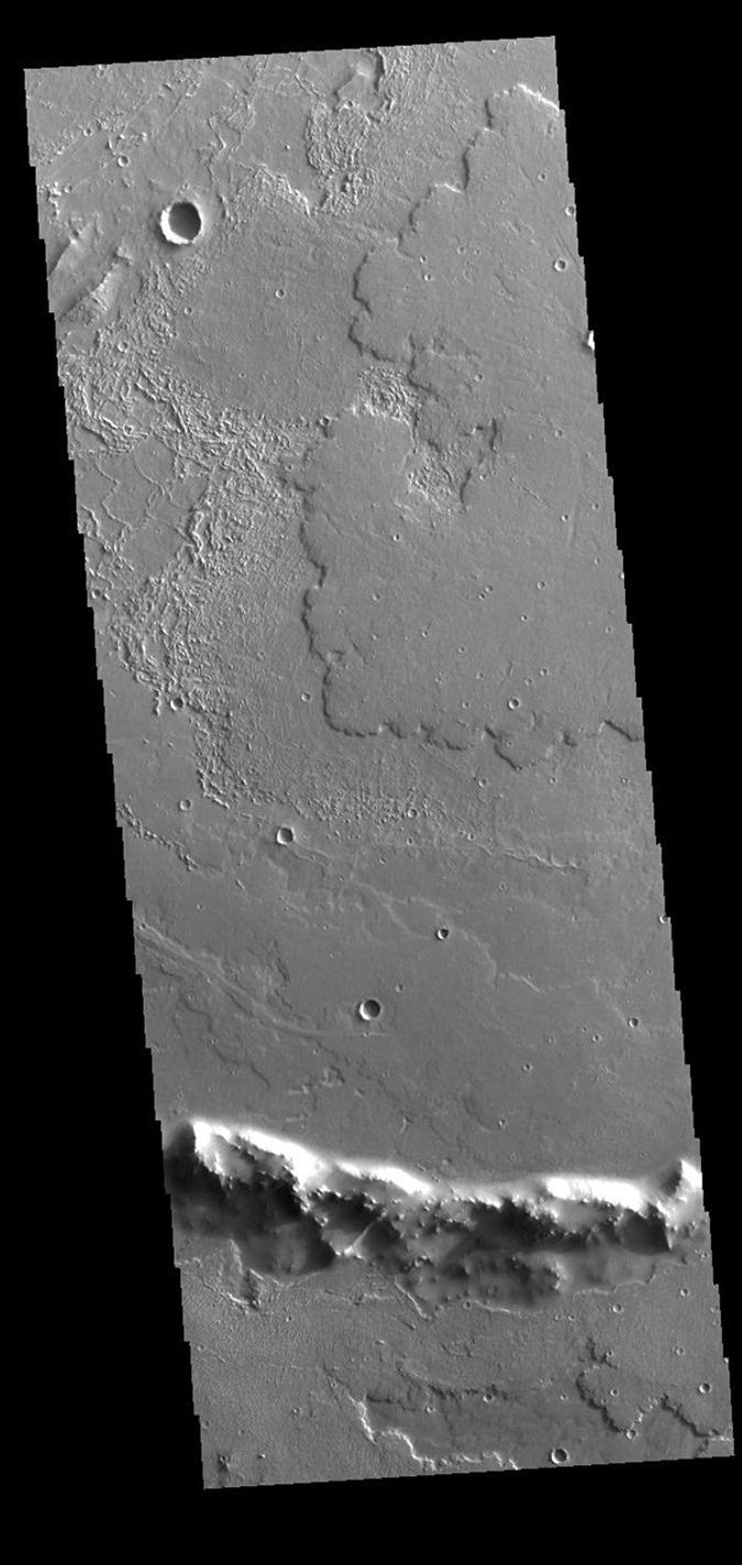 At the bottom of this image of Daedalia Planum is the uppermost rim of an impact crater. This image was captured by NASA's 2001 Mars Odyssey spacecraft.