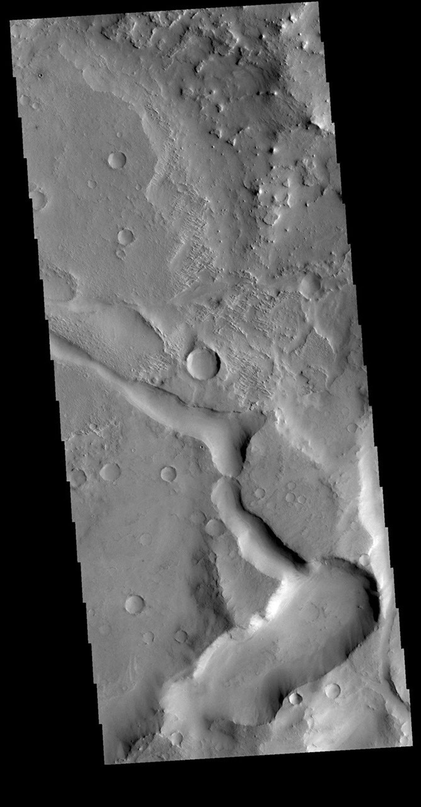 This image from NASA's Mars Odyssey is located in Terra Sabaea near the margin of Syrtis Major Planum. The channel-like feature at bottom is an unnamed. There is a high spot within the channel that would not let a fluid pass from one side to the other.