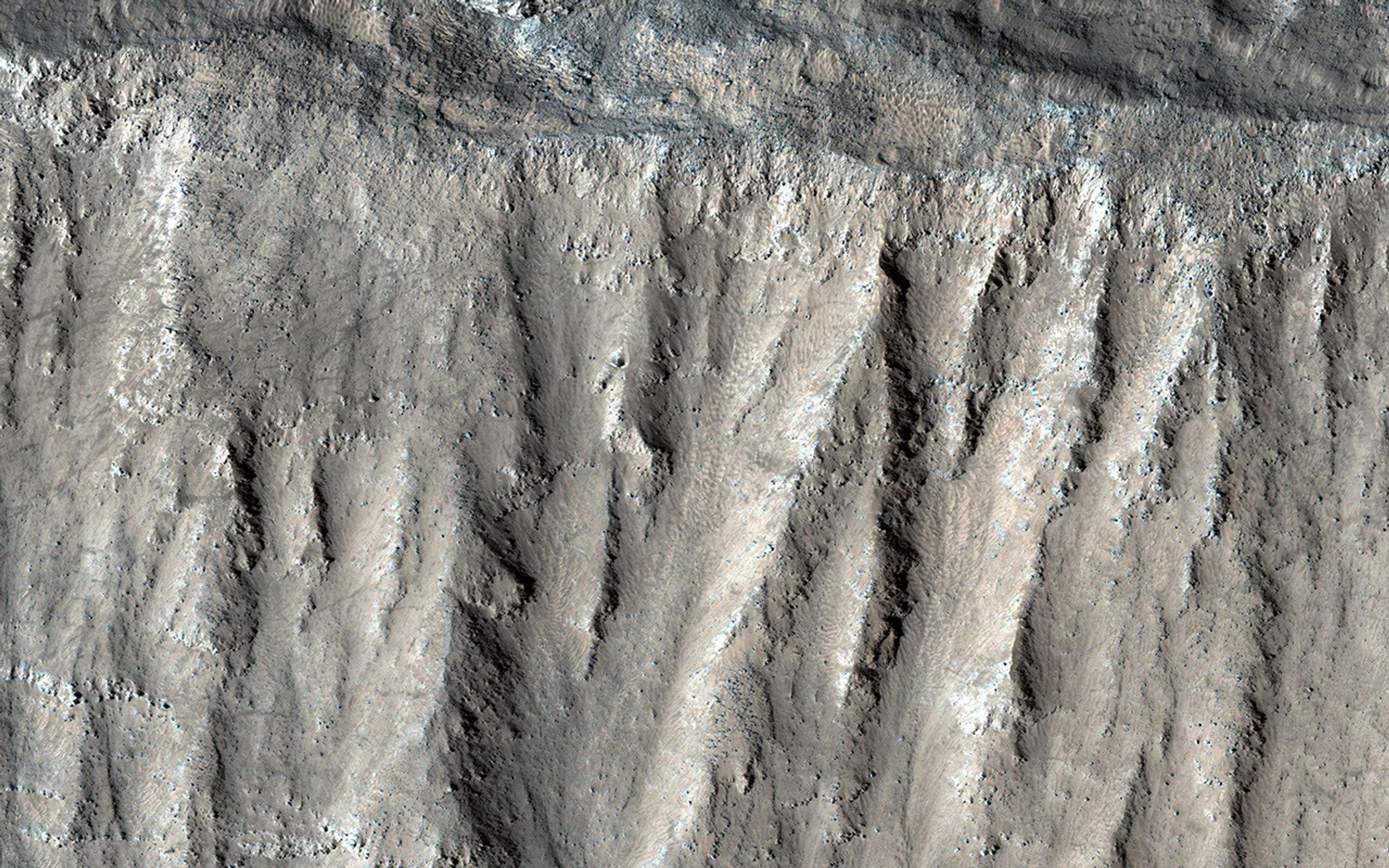 This image acquired on August 10, 2018 by NASA's Mars Reconnaissance Orbiter, shows part of the steep wall of the caldera (a large volcanic crater) at the top of Ascraeus Mons, one of Mars' giant volcanoes.