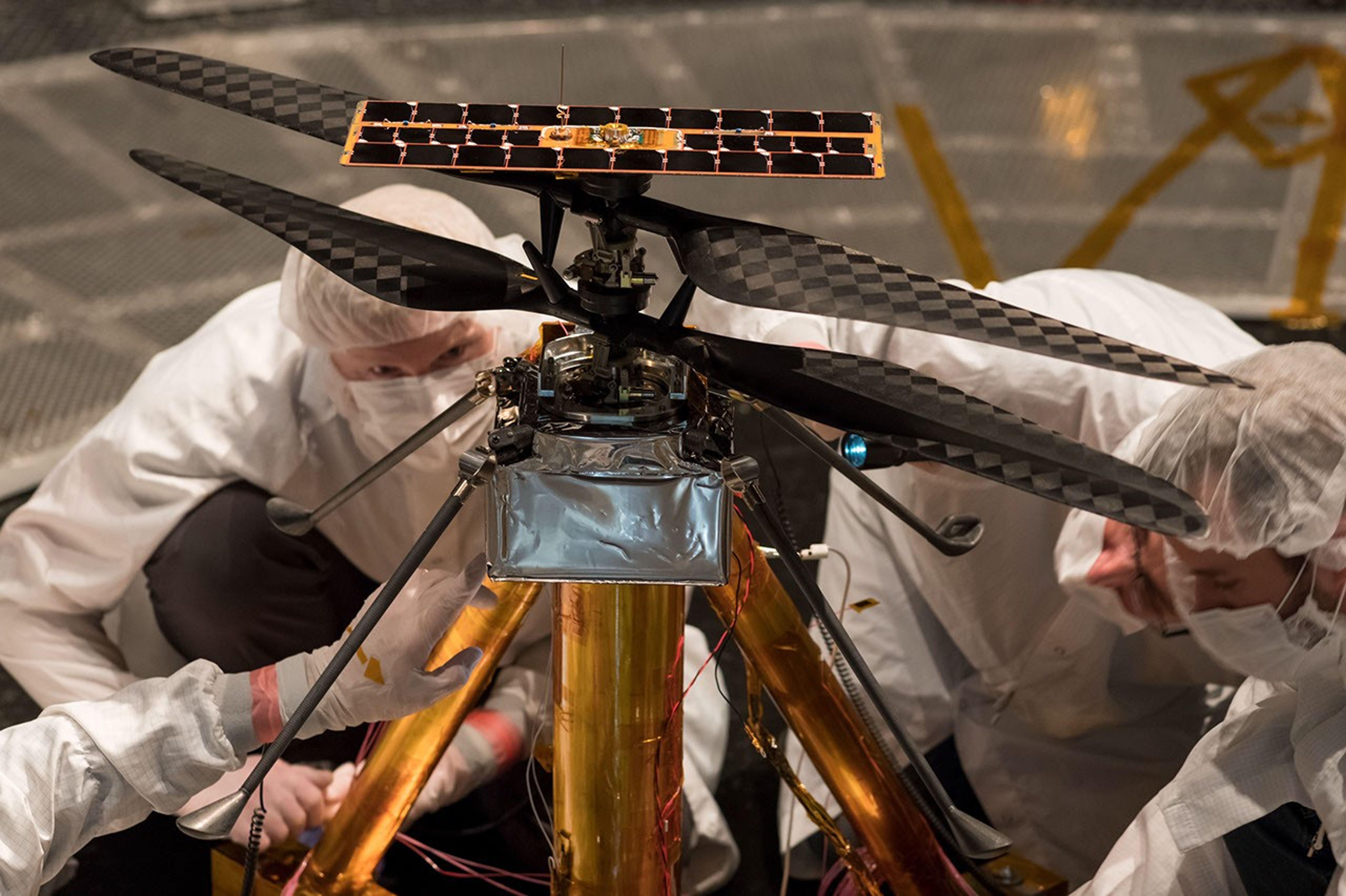 Members of the NASA Mars Helicopter team inspect the flight model (the actual vehicle going to the Red Planet), inside the Space Simulator at NASA's Jet Propulsion Laboratory in Pasadena, California, on Feb. 1, 2019.