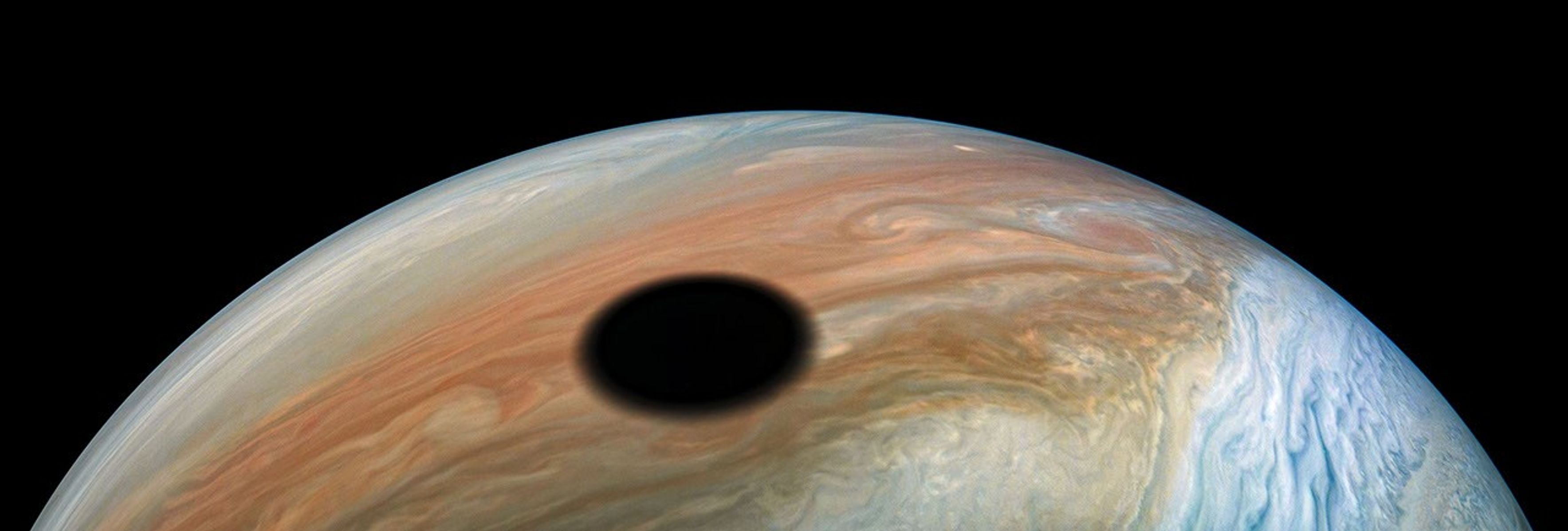 Jupiter's volcanically active moon Io casts its shadow on the planet in this dramatic image from NASA's Juno spacecraft.