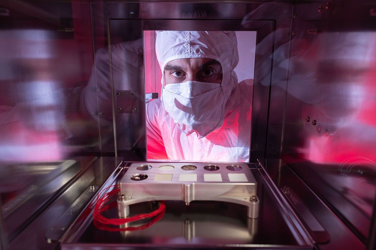 NASA scientist Trevor Graff peers at a calibration target, which will help fine-tune settings on the SHERLOC instrument carried aboard NASA's Perseverance Mars rover. The target carries the first spacesuit materials sent to Mars.