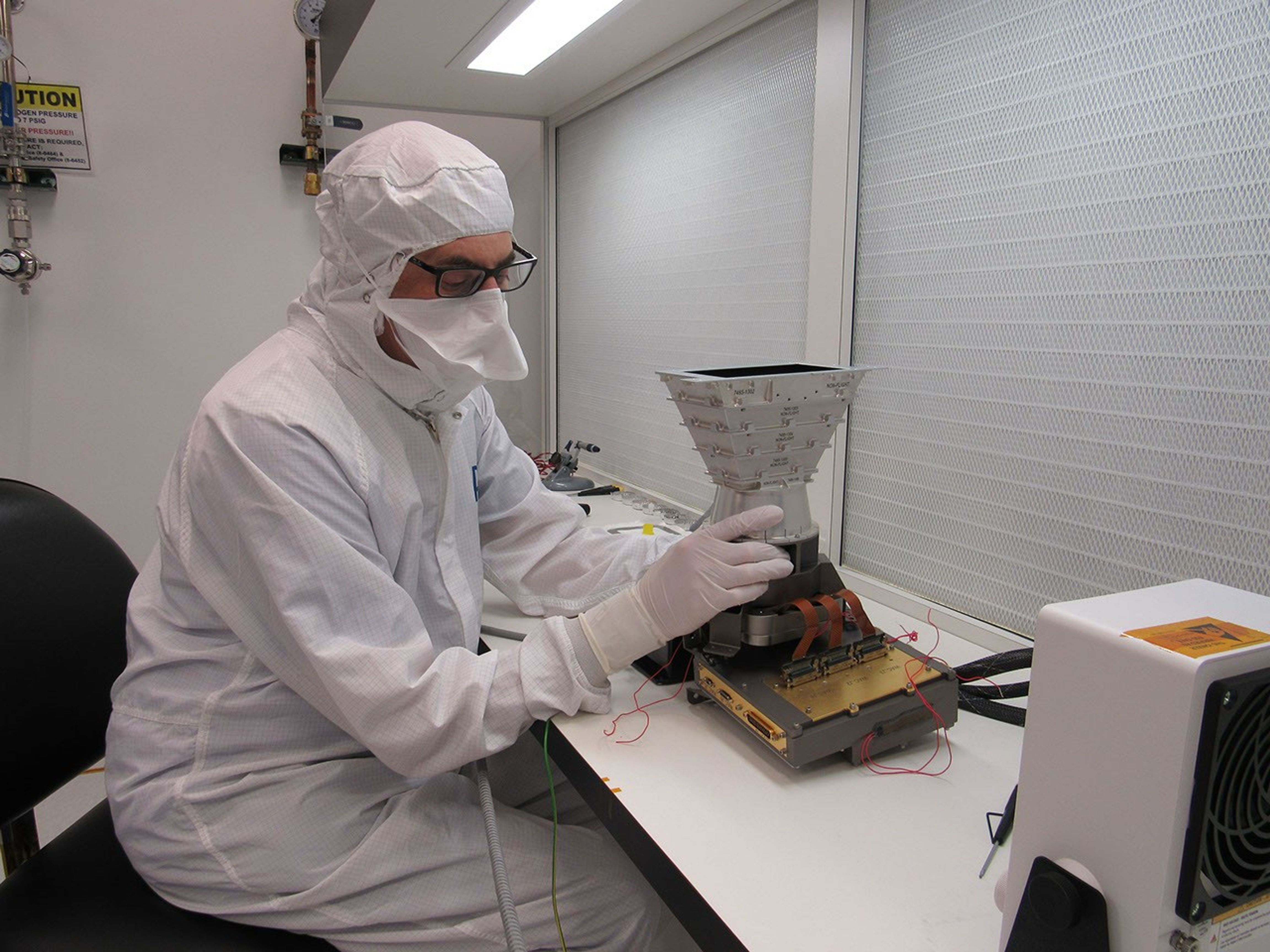 An engineer at the Johns Hopkins Applied Physics Laboratory (APL) works with an engineering model of part of the Europa Imaging System (EIS) that will fly aboard NASA's Europa Clipper.