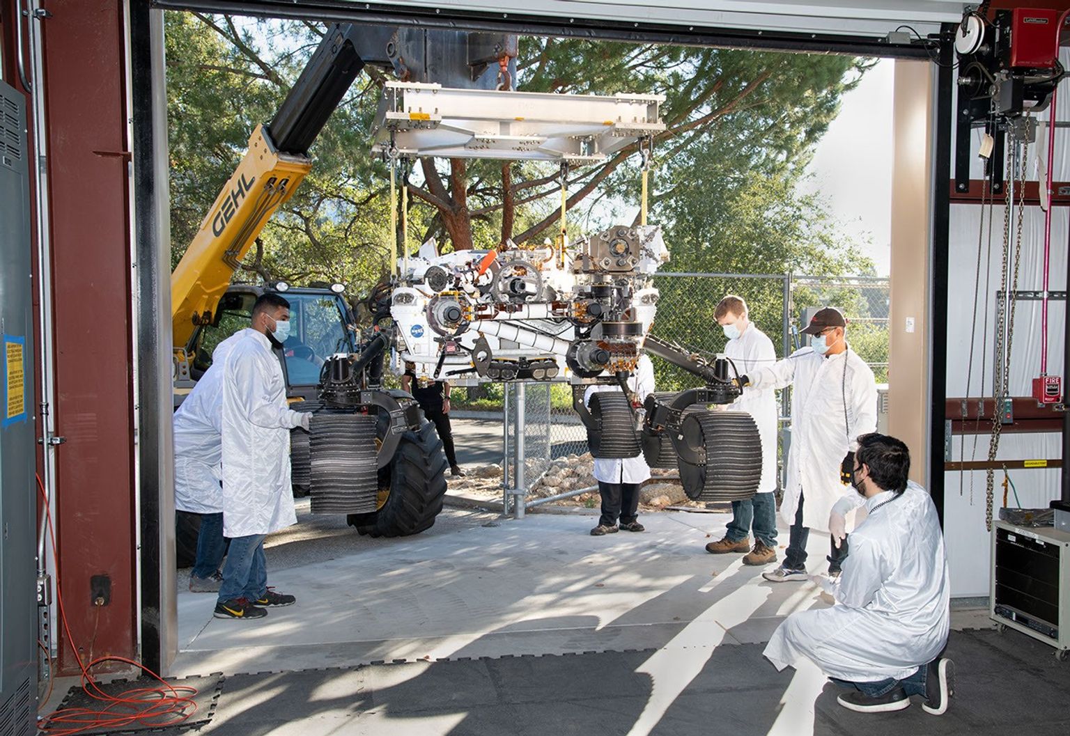 On October 29, 2021, a heavy-duty vehicle transports the Perseverance rover's engineering model, called OPTIMISM, from a test lab to the Mars Yard garage at JPL.