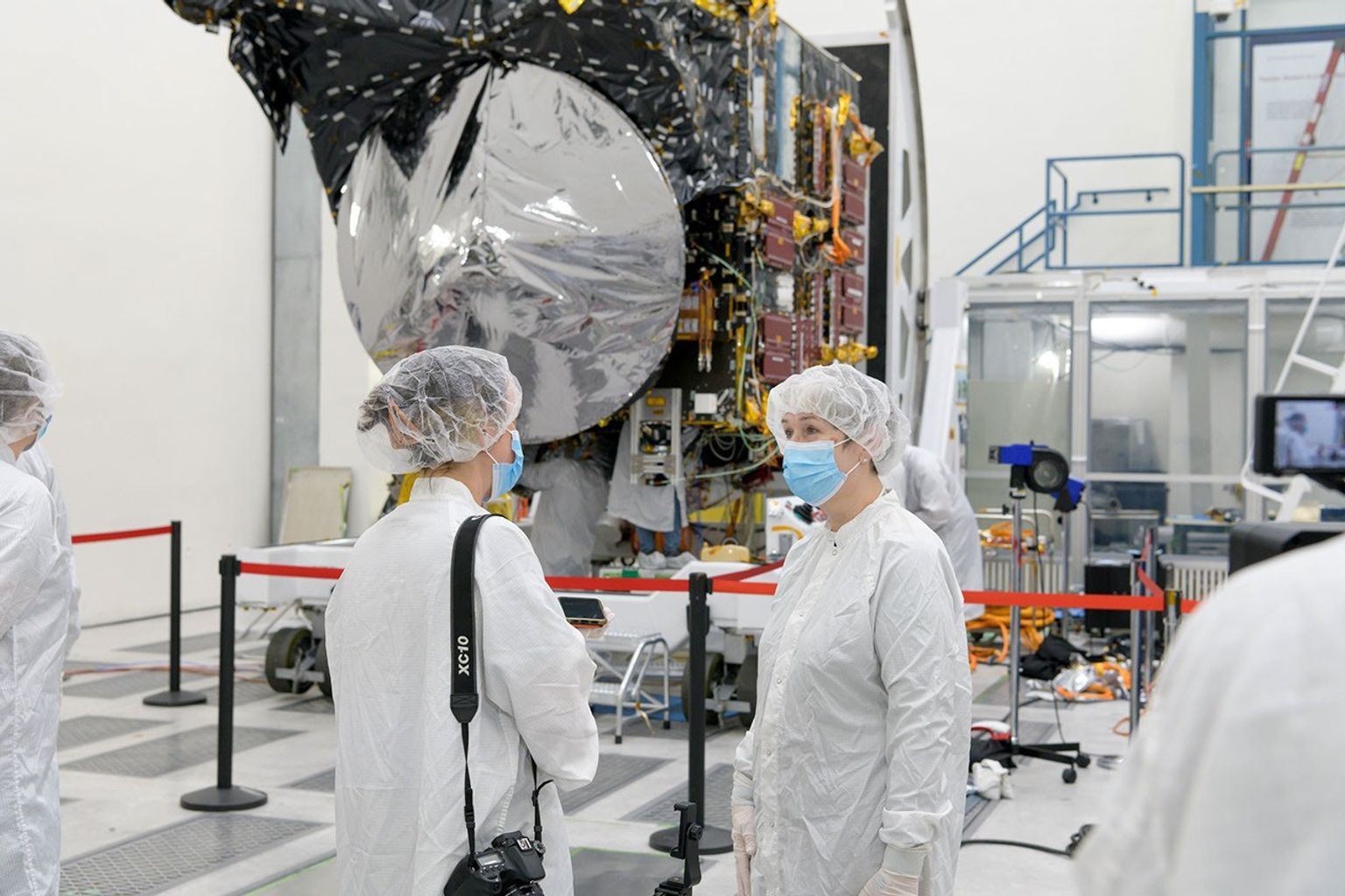 A member of the media interviews Lindy Elkins-Tanton, the principal investigator of NASA's Psyche mission, in front of the spacecraft on April 11, 2022, inside a clean room at JPL.