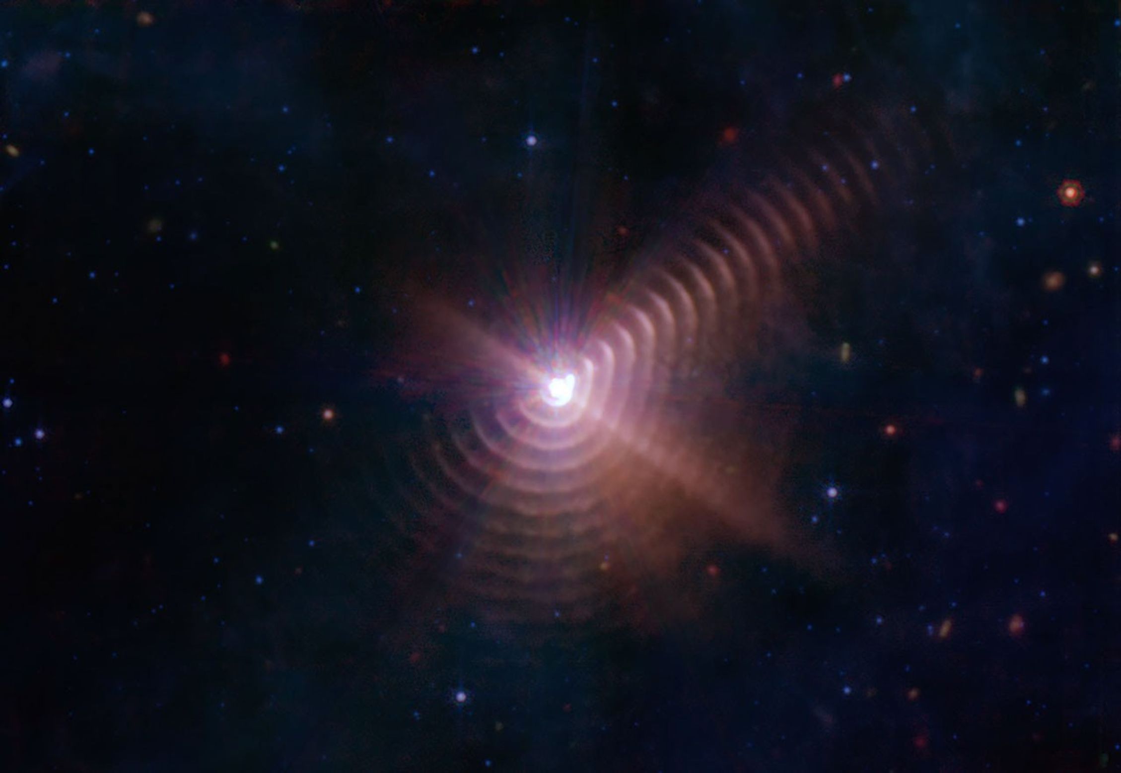 The two stars in Wolf-Rayet 140 produce shells of dust every eight years that look like rings, as seen in this image from NASA's James Webb Space Telescope. Each ring was created when the stars came close together and their stellar winds collided.