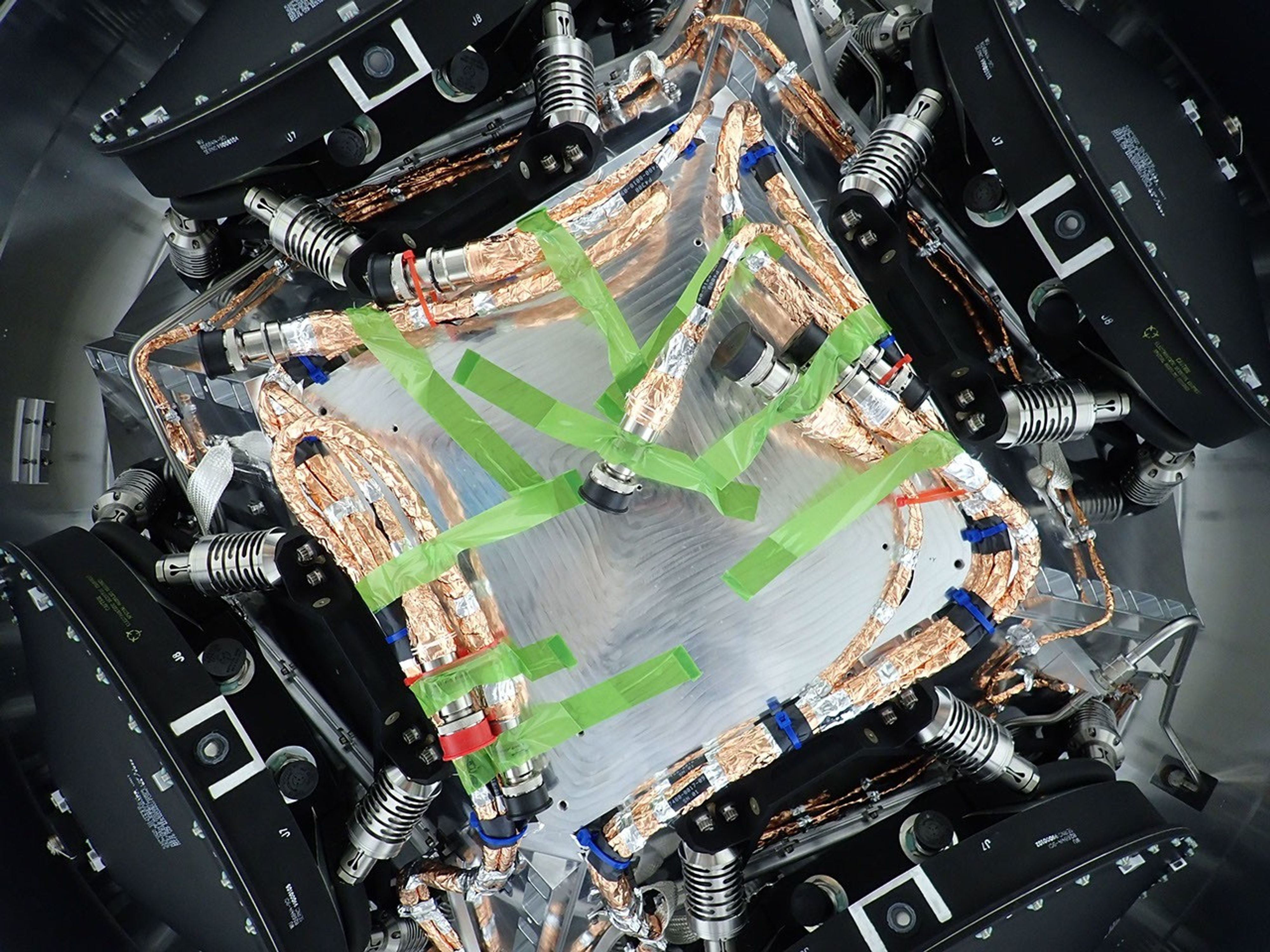 All four of the reaction wheels installed onto NASA's Europa Clipper are visible in this photo, which was shot from underneath the main body of the spacecraft while it is being assembled.