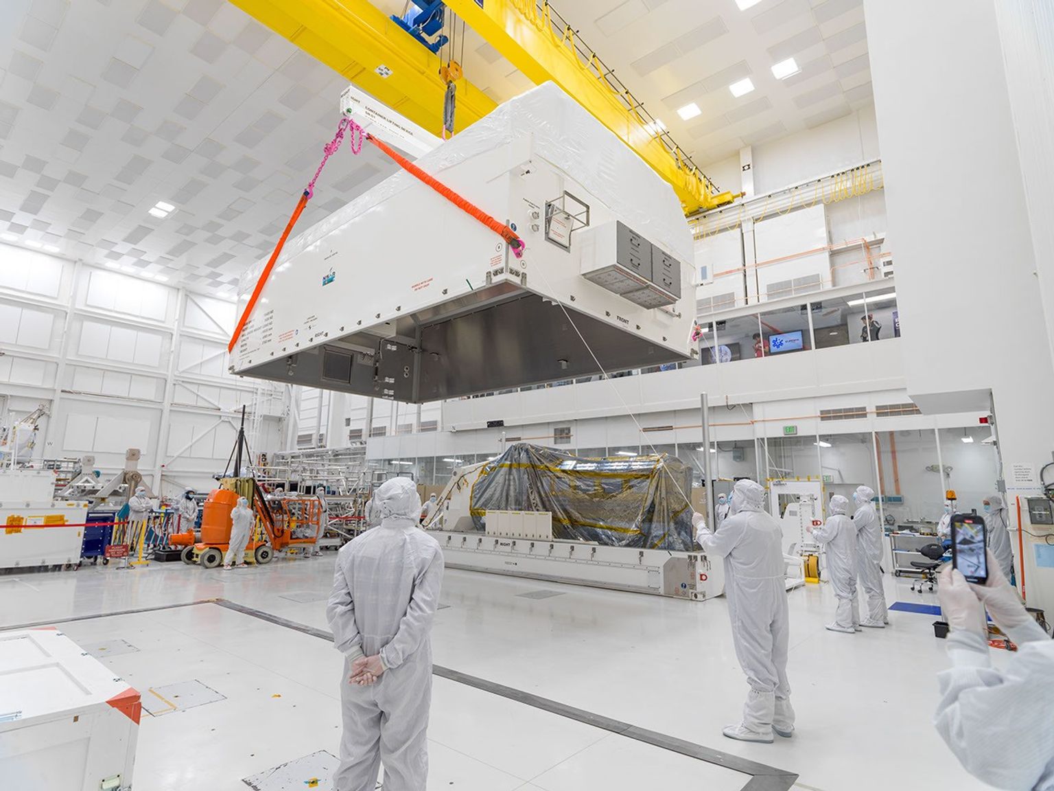 In a JPL clean room, engineers and technicians move the lid of container into position to lower it over the NISAR science payload. The payload was shipped on March 3, 2023, to India, where it will be combined with the satellite body.