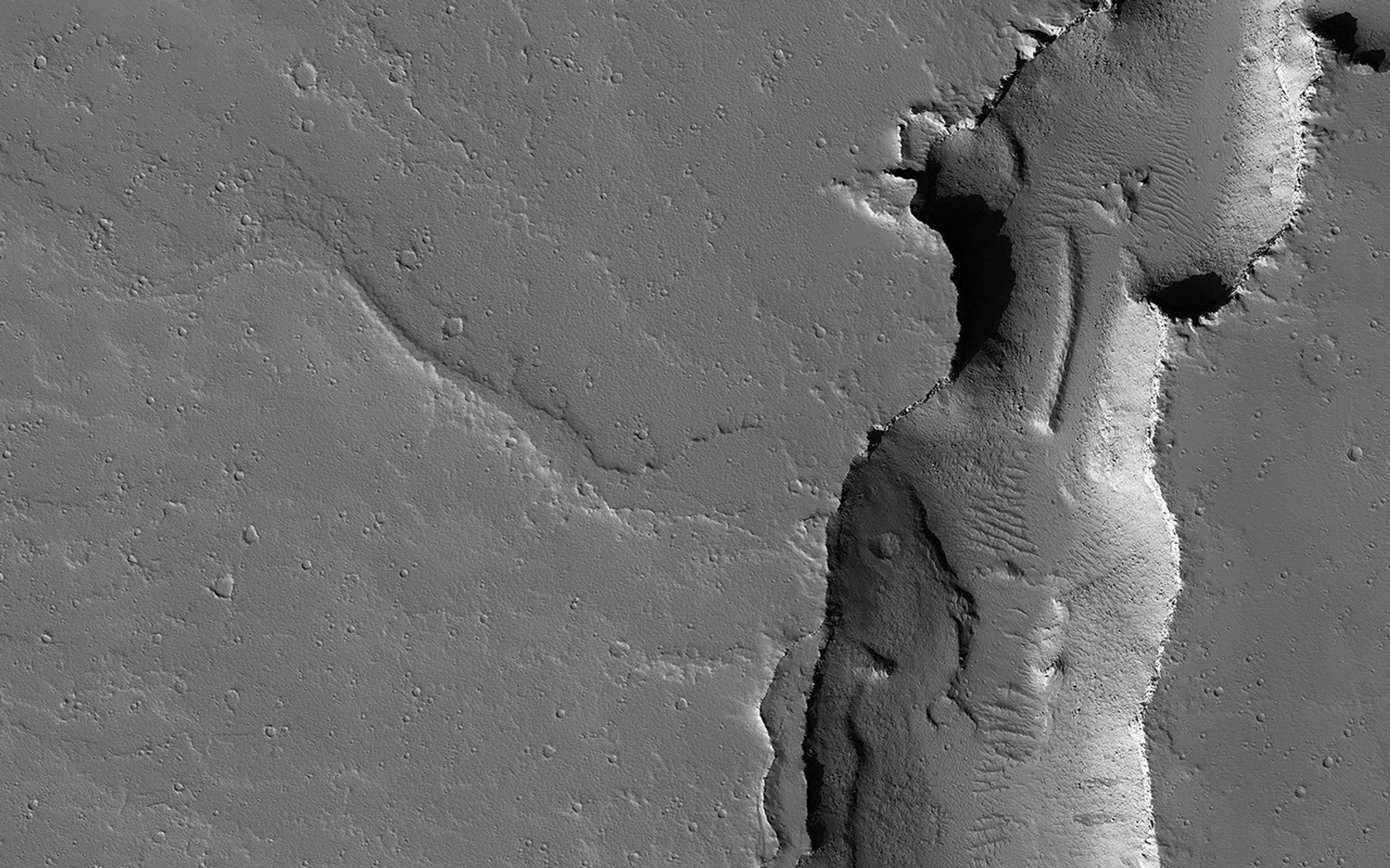 This image acquired on August 29, 2022 by NASA's Mars Reconnaissance Orbiter shows two cross-cutting depressions that may have been formed by the collapse of weak terrain along pre-existing faults.