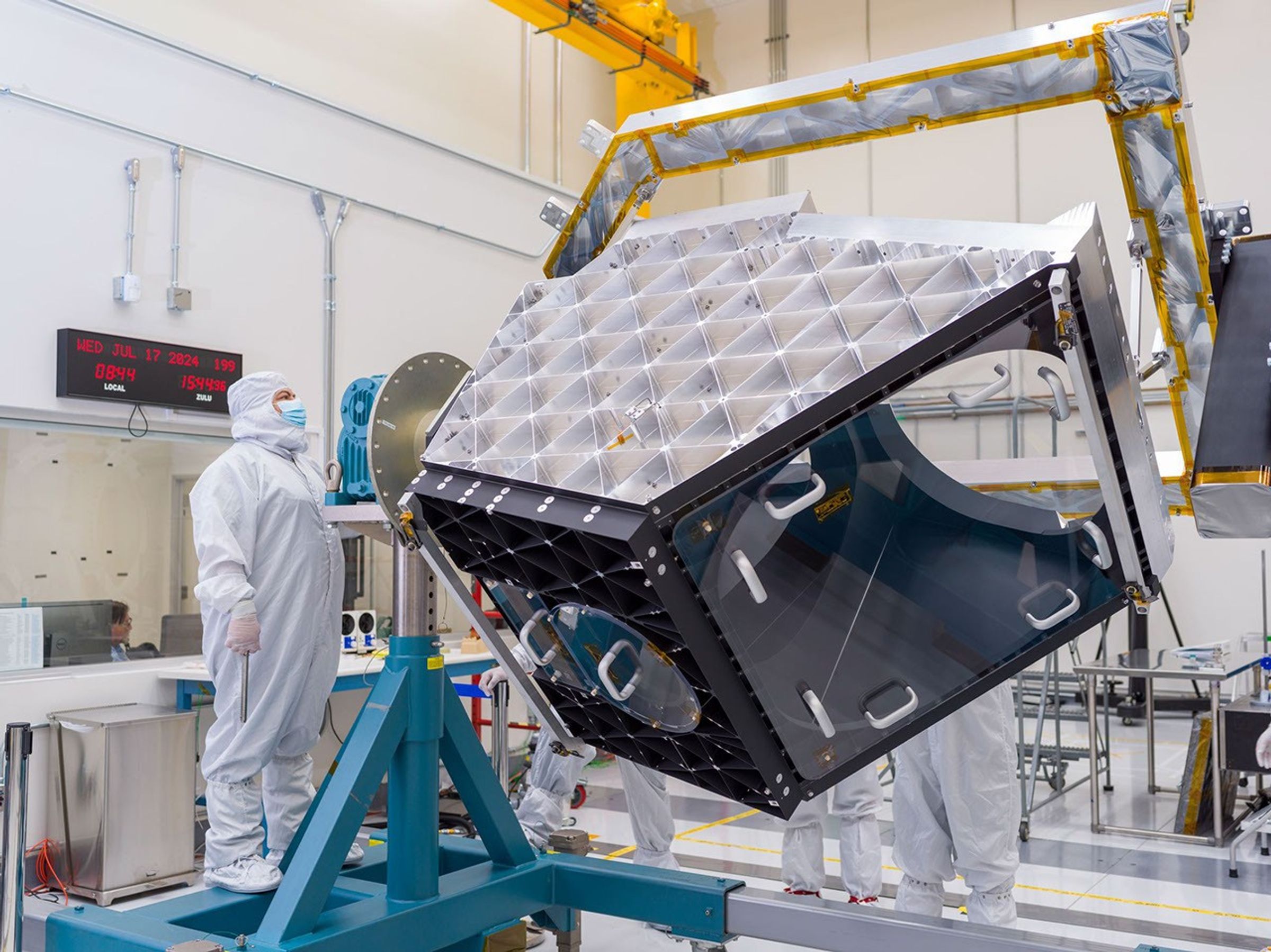 A technician operates articulating equipment to rotate NEO Surveyor's aluminum optical bench in a clean room at NASA's Jet Propulsion Laboratory in Southern California on July 17, 2024.
