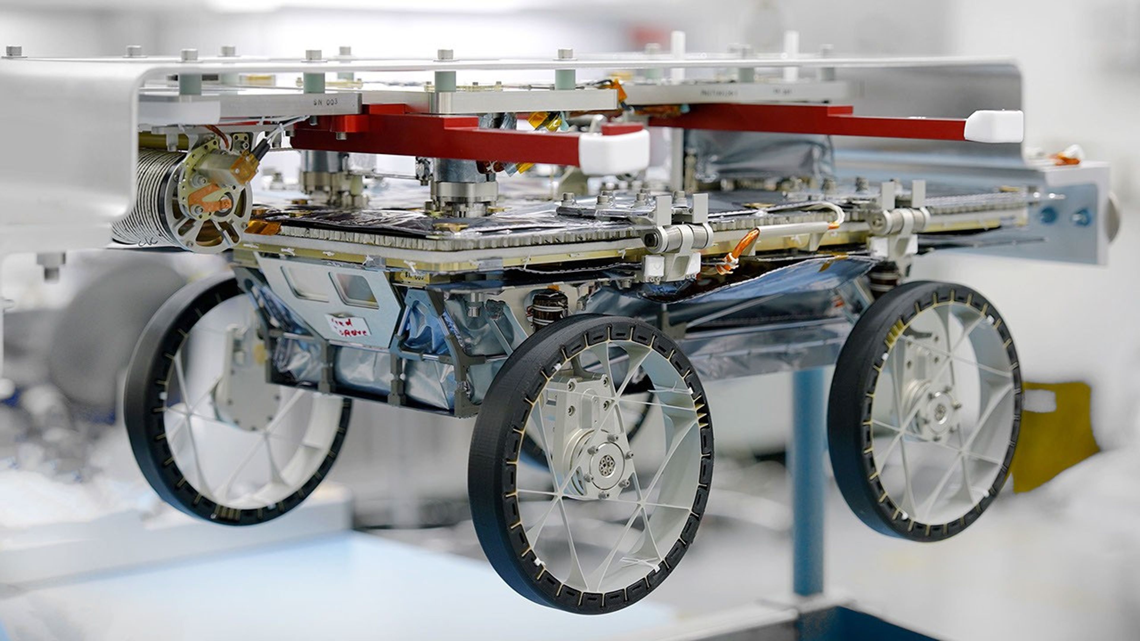 One of three small lunar rovers that are part of a NASA technology demonstration called CADRE is attached to a fixture in a clean room at the agency's Jet Propulsion Laboratory on Jan. 29, 2025.