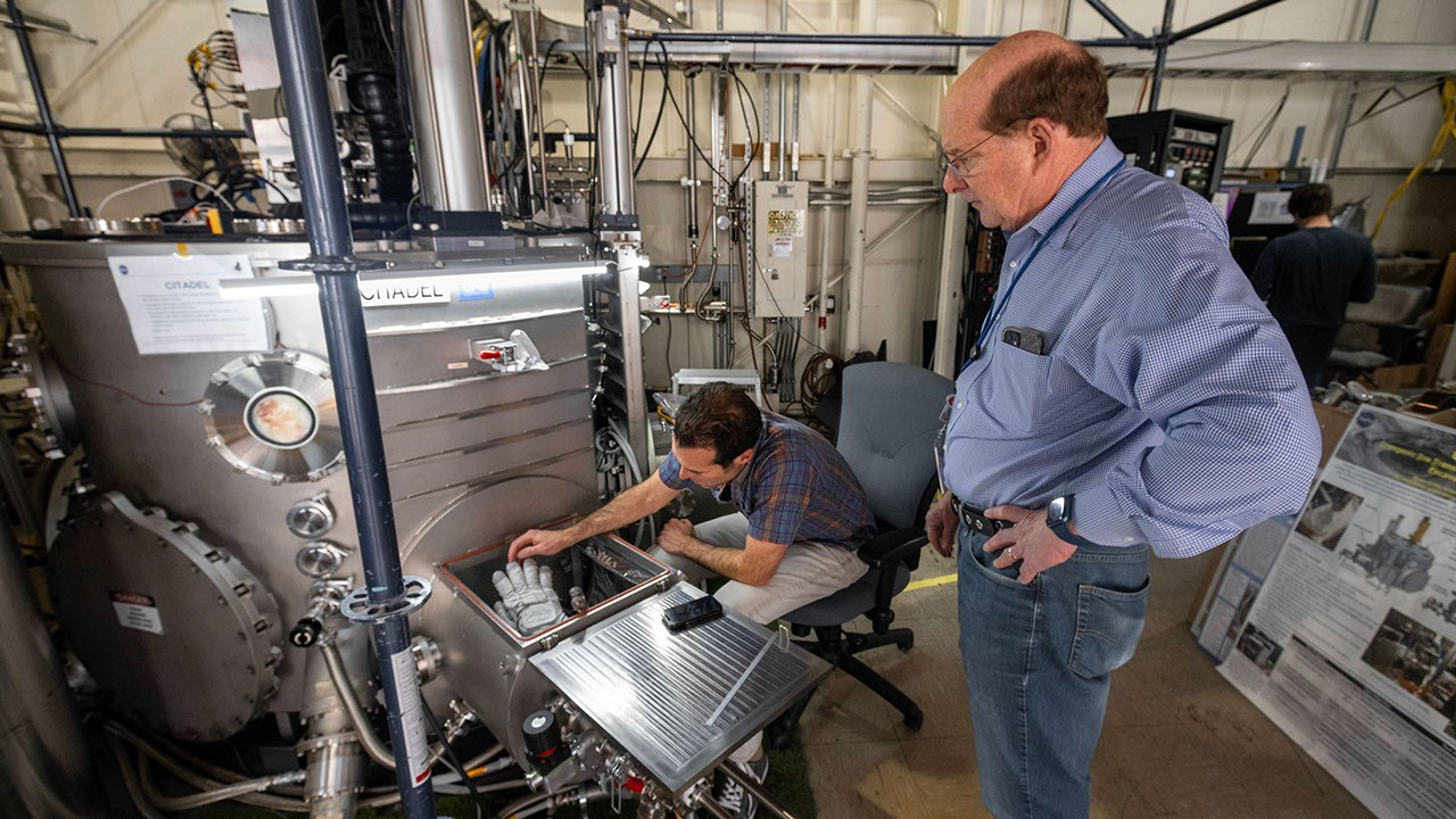 Engineers with NASA Johnson and the NASA Engineering and Safety Center ready an astronaut glove for insertion into the main CITADEL chamber at JPL.
