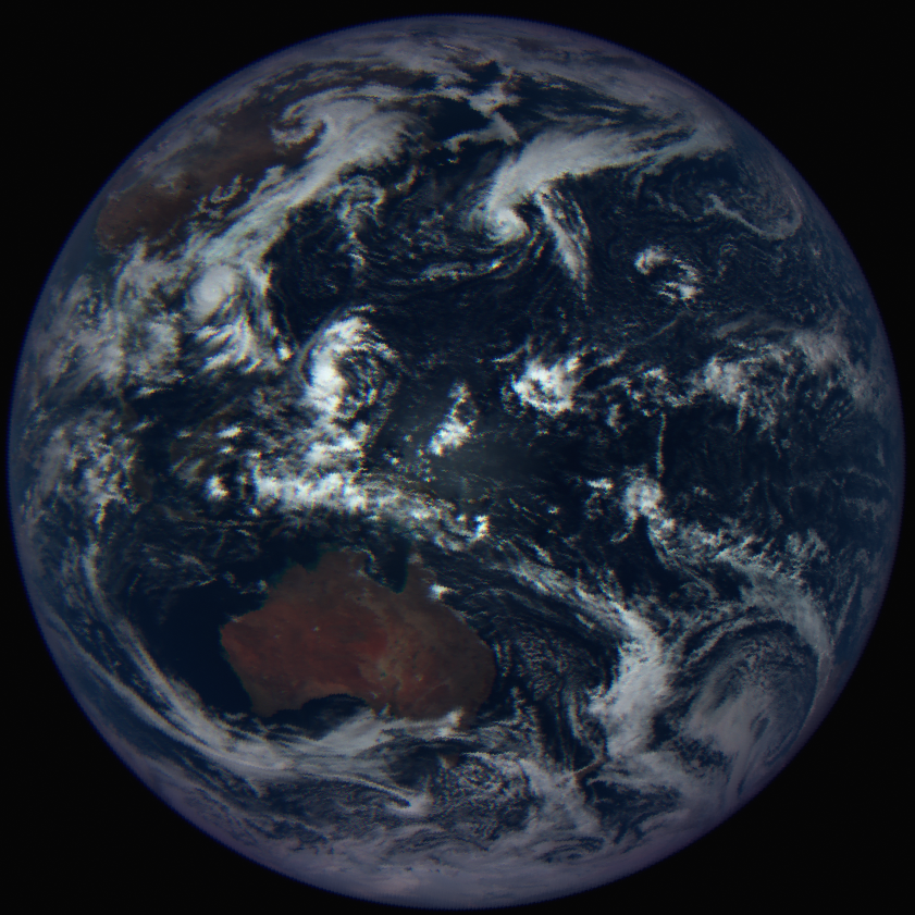 The full disk of Earth against the black of space. Australia is near the center of the image, a dark brown landmass surrounded by ocean and white clouds. The far eastern edge of Asia peeks over the horizon on the left side.