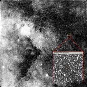 Black and white star field with a red inset showing a close up view with orange crosshairs around a tiny white dot, representing the interstellar comet.