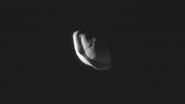 A gray moon that looks somewhat like a flying saucer is seen against the darkness of space in this Cassini spacecraft image.