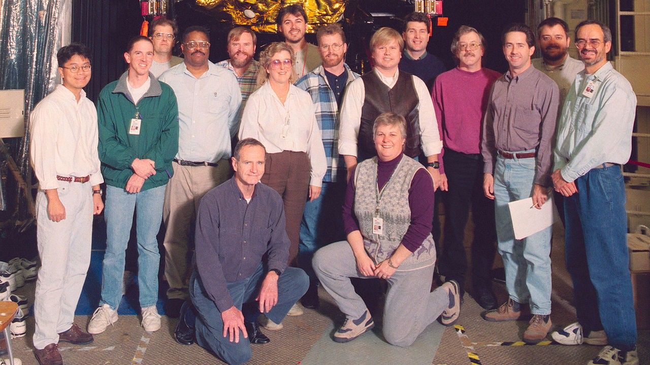 Color image of people standing in front of a spacecraft.