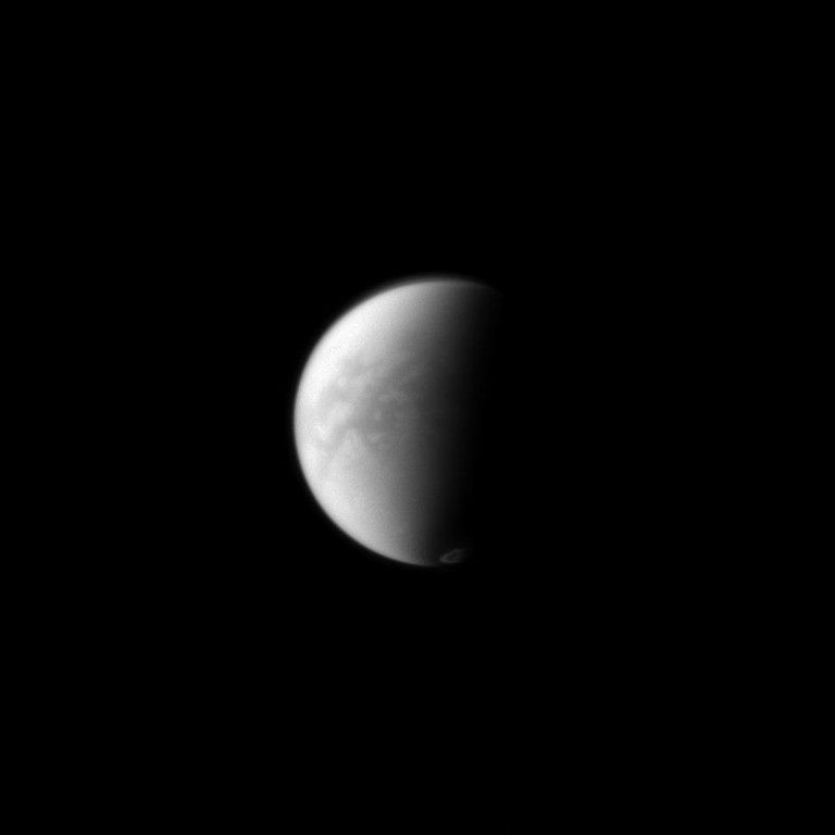 The Cassini spacecraft simultaneously peers through the haze in Titan's equatorial region down to its surface and captures the vortex of clouds hovering over its south pole just to the right of the terminator on the moon's dark side. The image was taken on Sept. 20, 2012.
