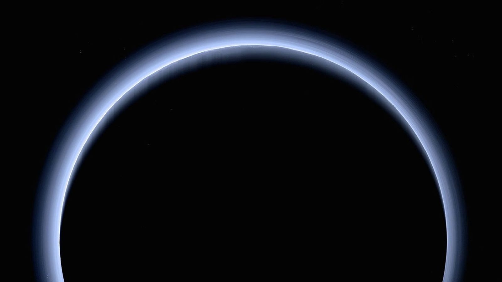 Crescent of Pluto as a blue haze over a dark orb.