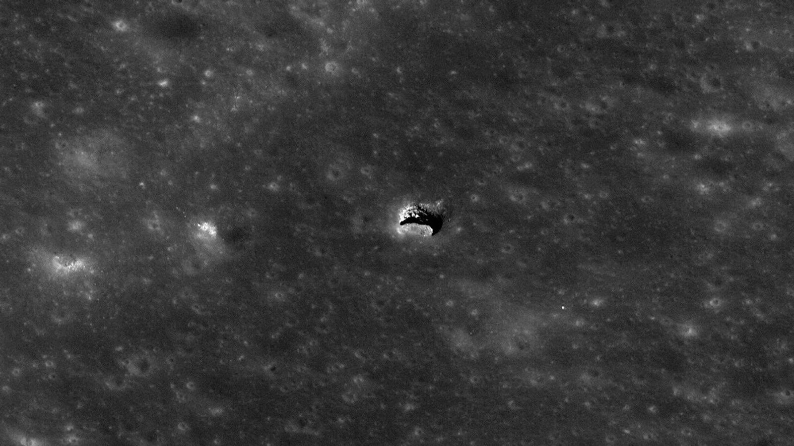 Satellite image of the Moon’s surface. In the middle of the image, the surface is sharply interrupted by what appears to be an opening in the roof of a cave. The landscape is illuminated at a low angle, revealing a small part of what looks like a larger void below the opening.