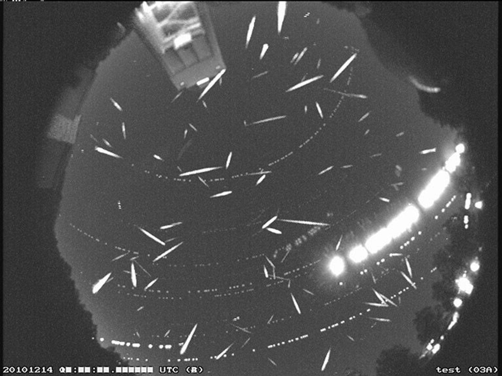 Dozens of bright meteor streaks crossing a dark night sky in a composite image from the peak of the Geminid meteor shower