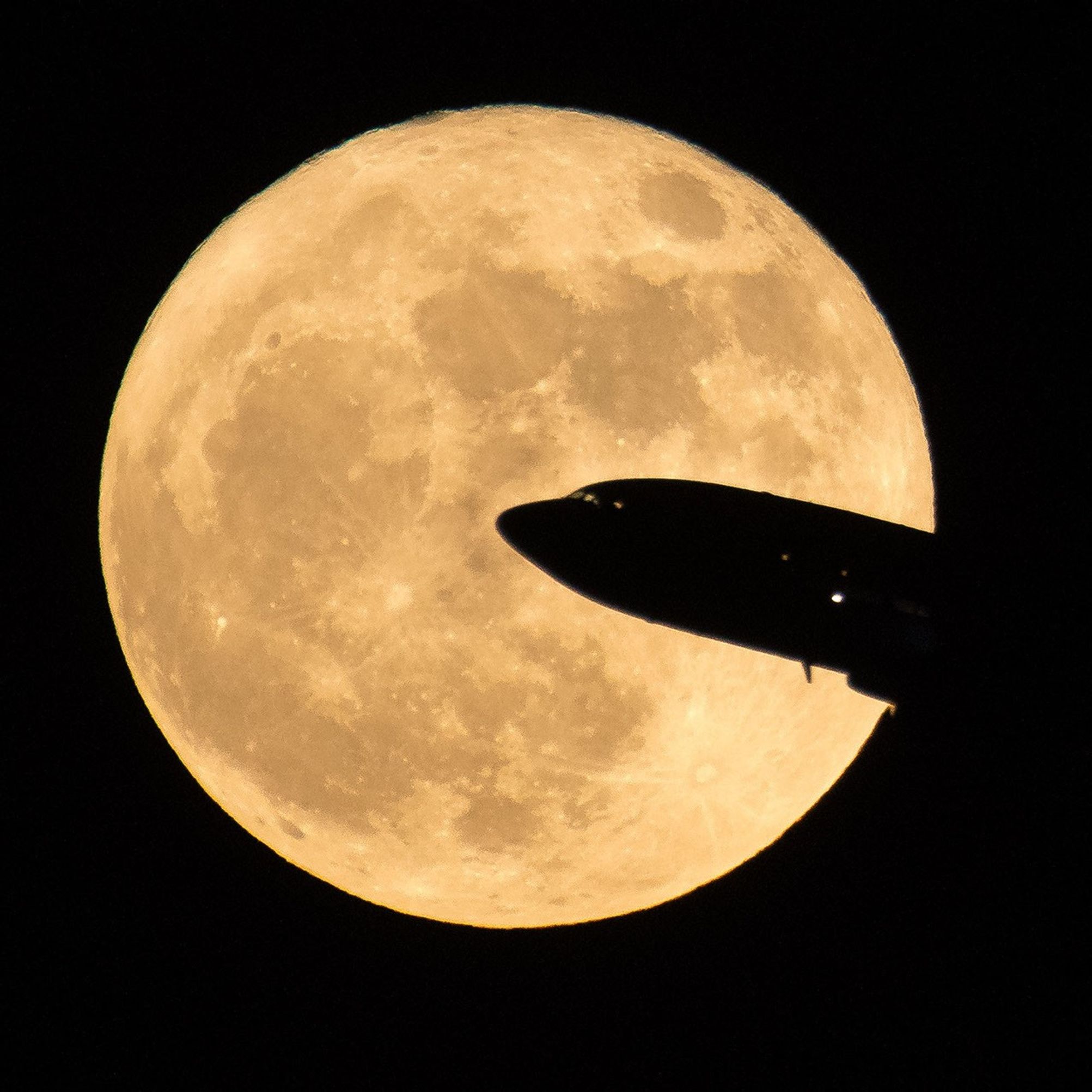 An airline flies across the face of the Moon in this forced perspective image that makes the airplane seen big and the Moon seem small.