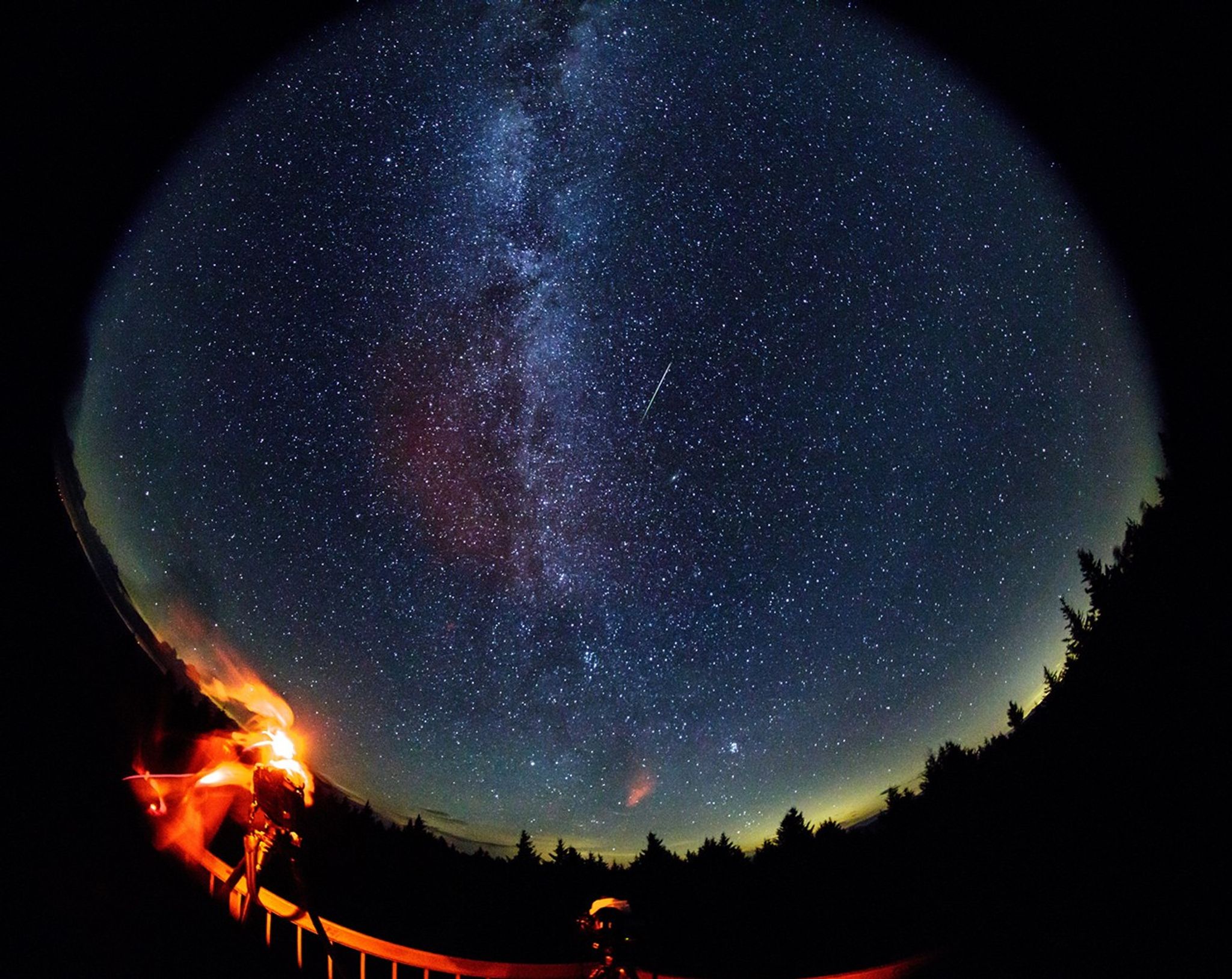 Meteor streak across dark sky.