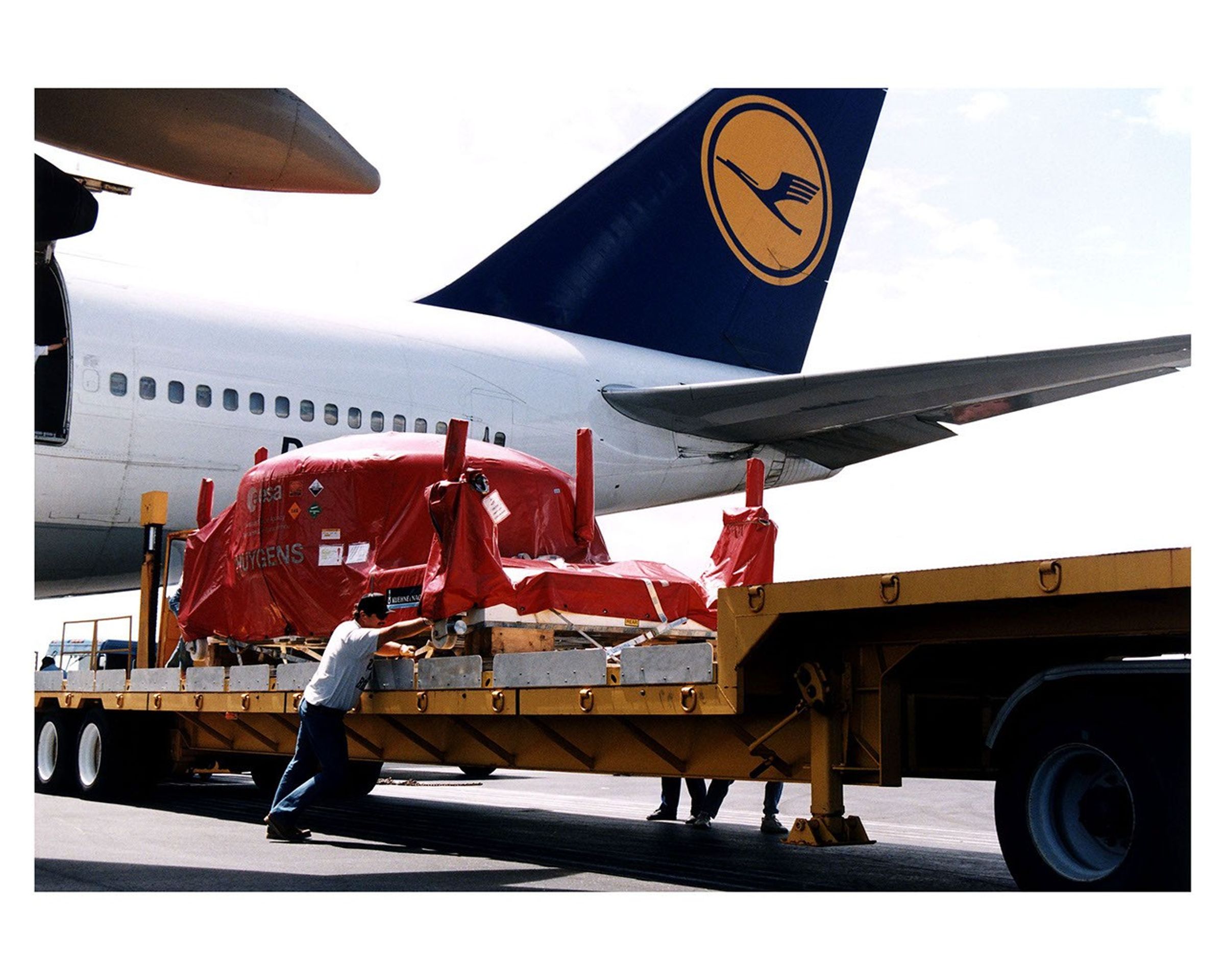 Man pushing covered spacecraft on trailer.