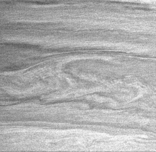 In this Cassini image, the large-scale curvilinear pattern suggests flow around the vortices in the center of the image.