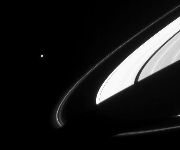 Saturn's moons Janus and Atlas along side the shadowy rings