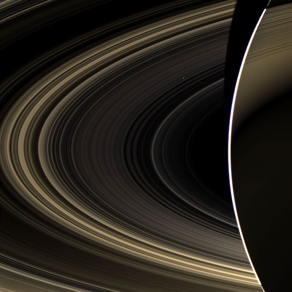Peering over the shoulder of giant Saturn, through its rings, and across interplanetary space, NASA's Cassini spacecraft spies the bright, cloudy terrestrial planet, Venus.