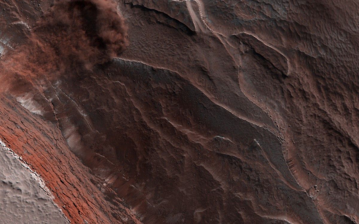layers of rock and ice, seen from above, with a cloud of dust where some material has slipped downhill