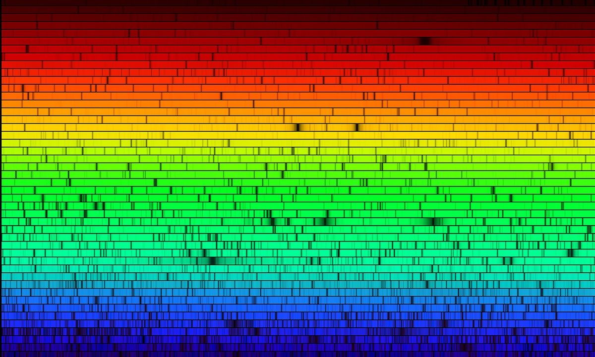 A high-resolution version of the spectrum of our Sun with colors descending from red to orange to yellow to green to blue.