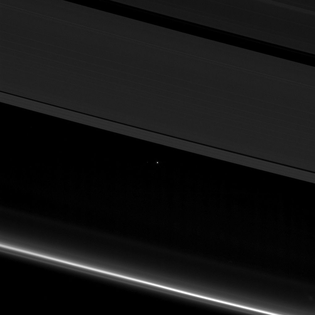 A view of planet Earth as a point of light between the icy rings of Saturn