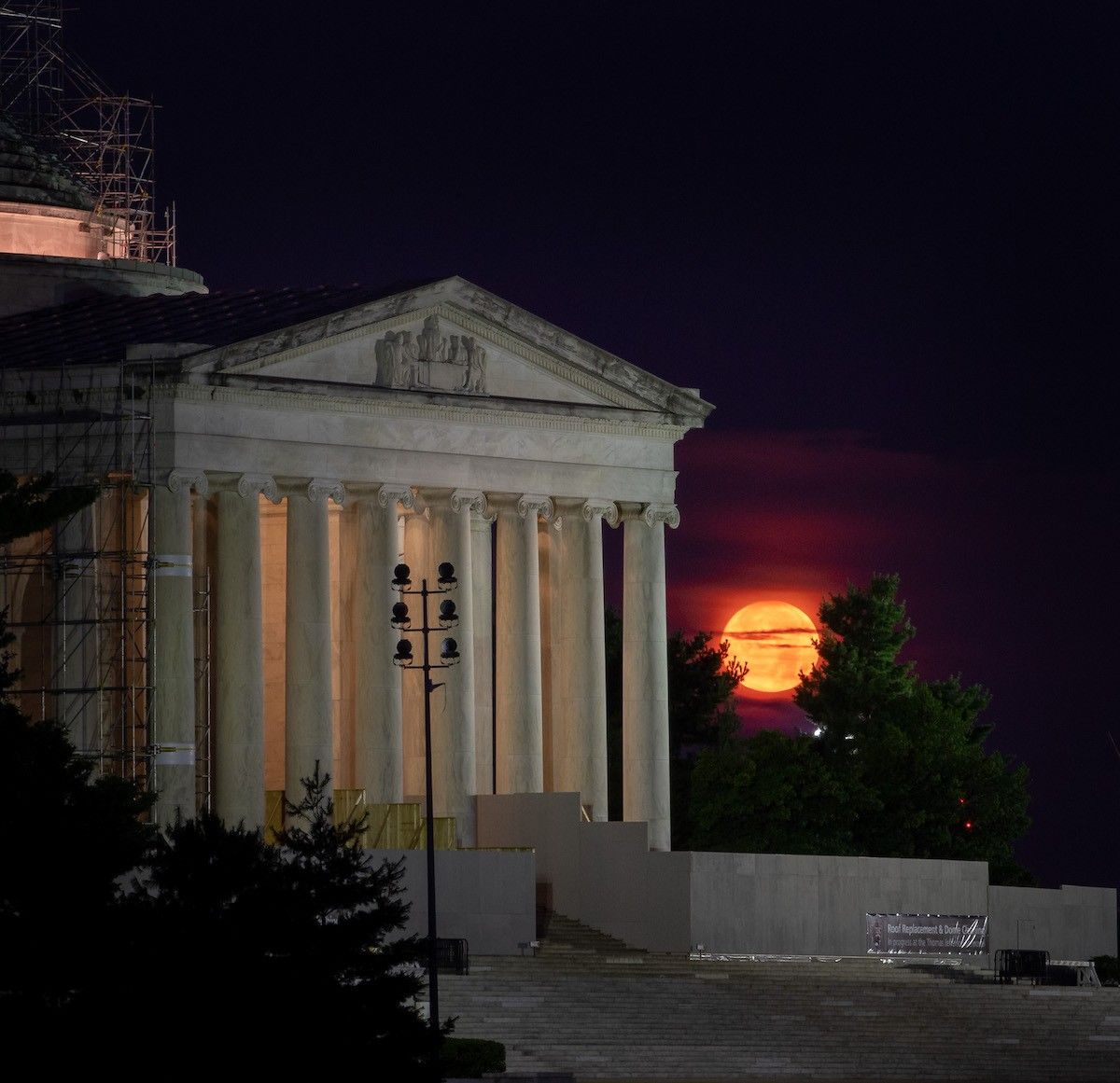 orange moon seen next to columned building