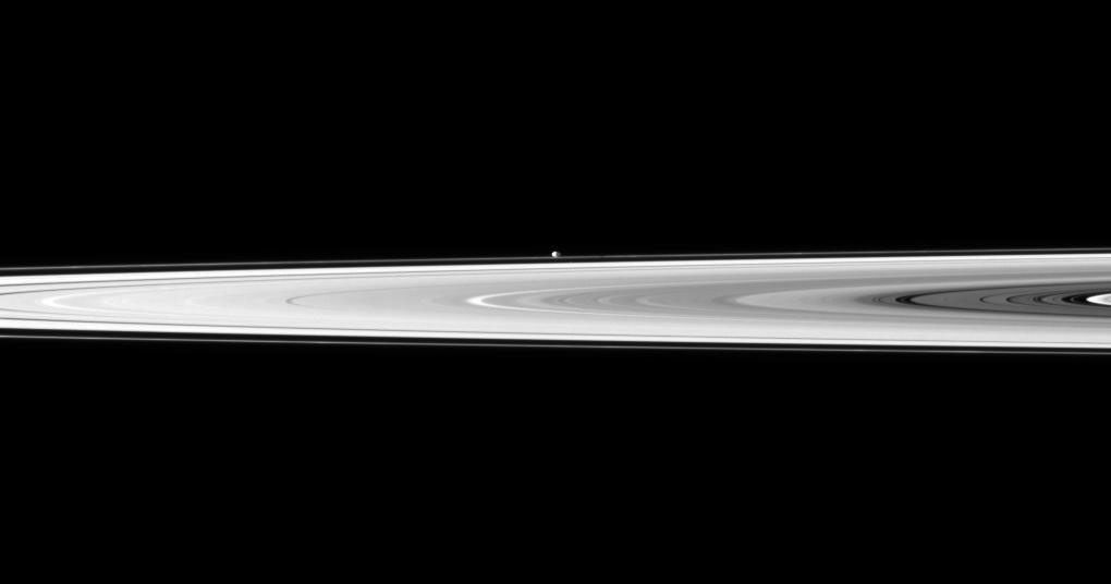 The tiny moon Pandora appears beyond the bright disk of Saturn's rings.