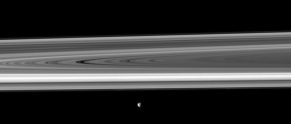 Saturn's moon Janus passes before the planet's rings