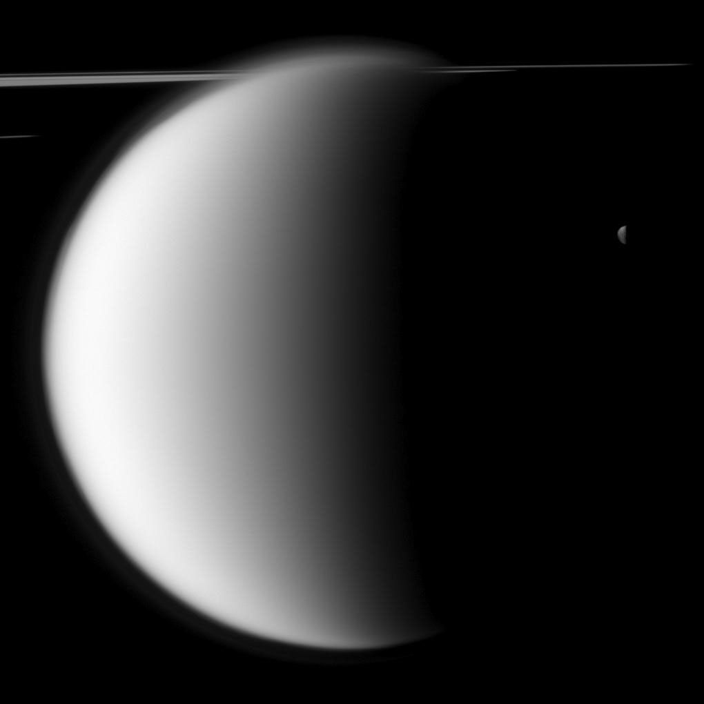 The Cassini spacecraft captures a "mutual event" between Titan and Mimas in front of a backdrop of the planet's rings.