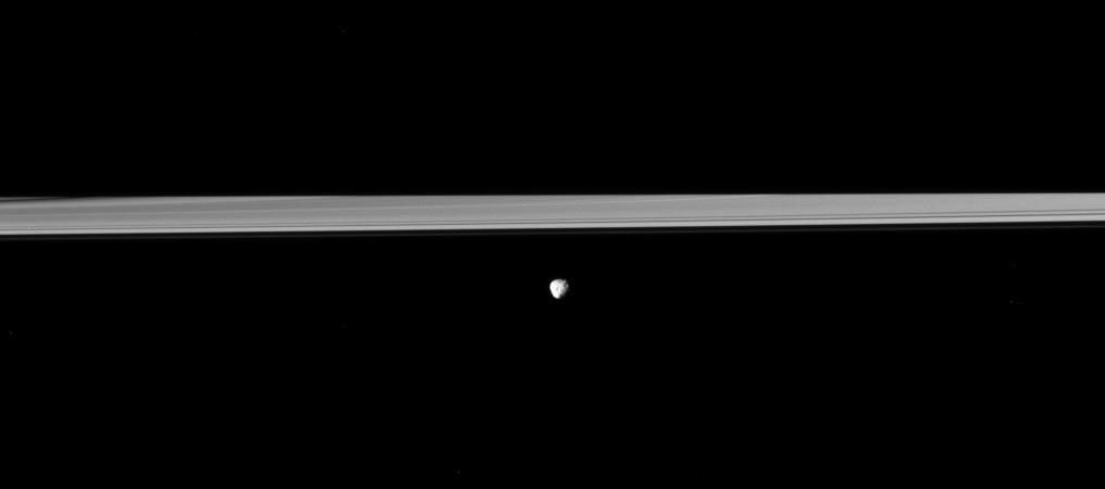 Saturn's moon Janus orbits in front of the rings, which are partially darkened by the shadow of the planet in this Cassini spacecraft view.