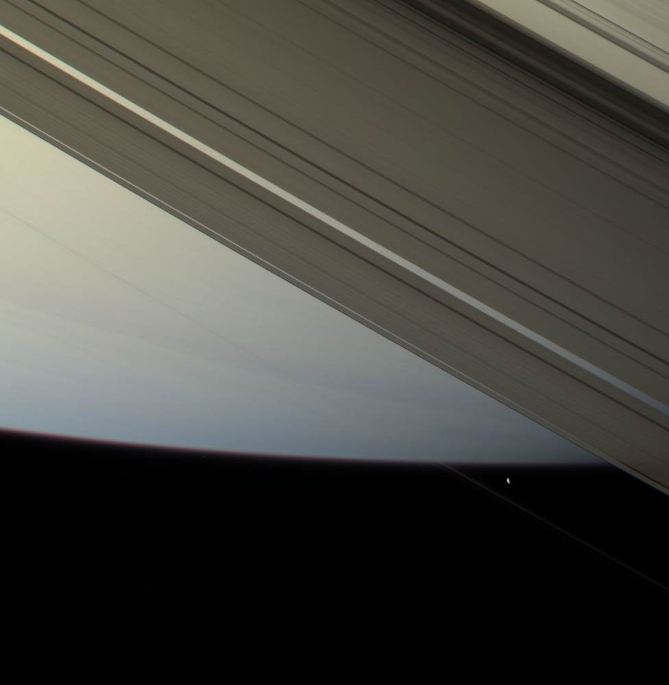 The F ring shepherd moon Prometheus touches the face of Saturn once more before moving off into blackness and continuing in its orbit.