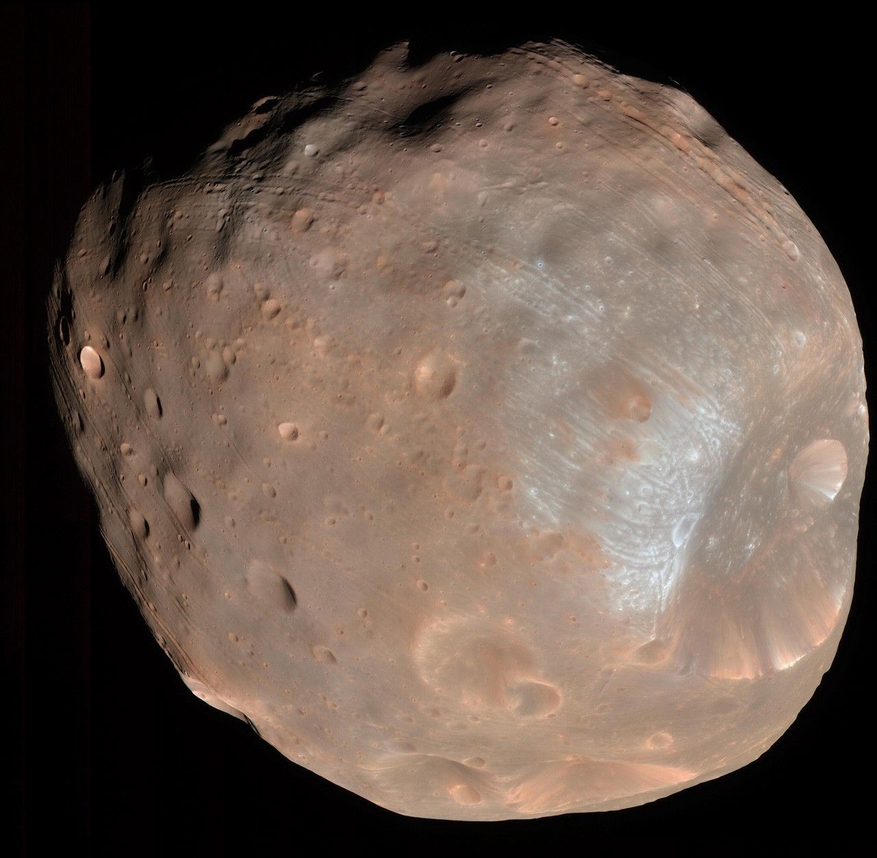Small reddish moon with huge impact crater on one end.