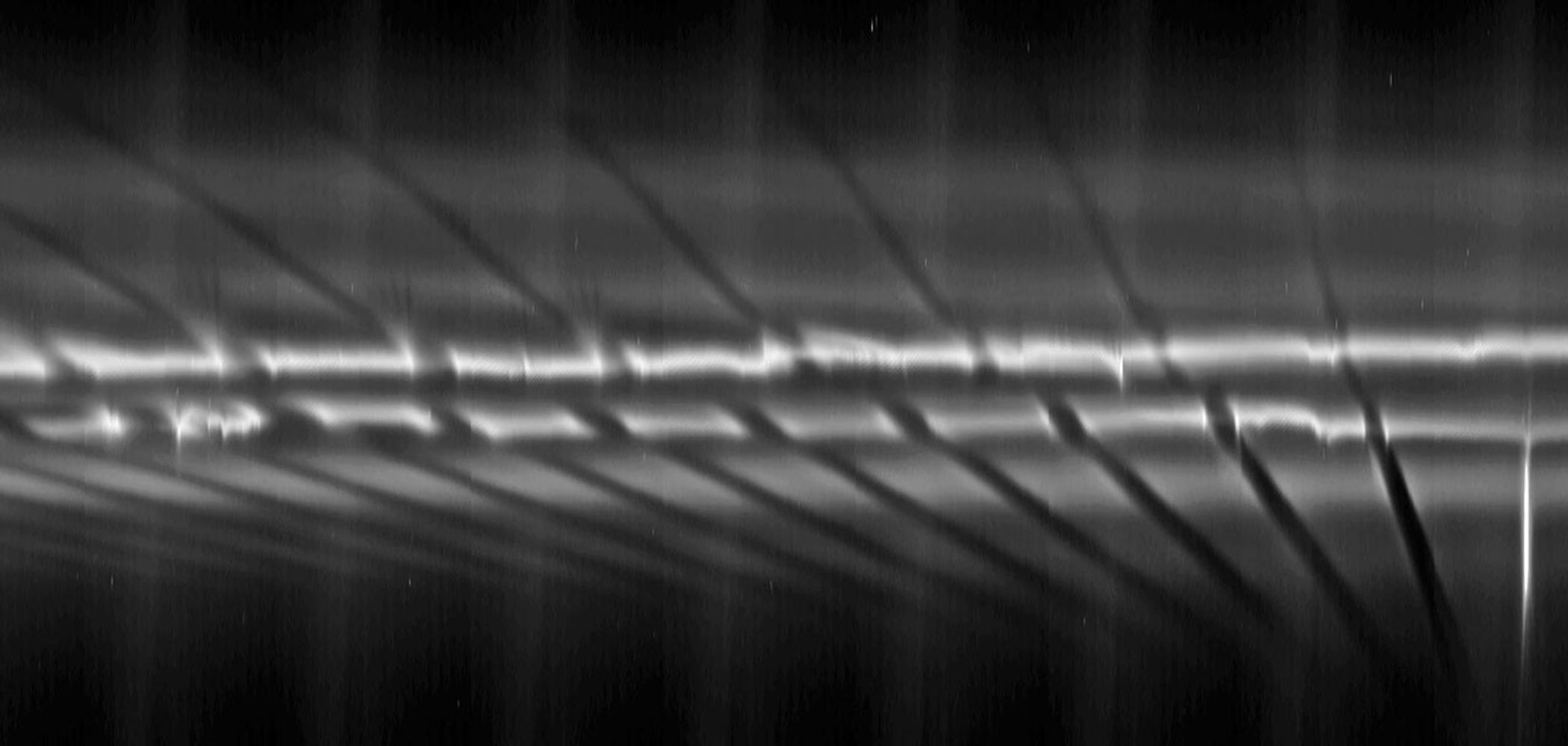 From right to left in the mosaic, each fan appears dark above the bright core of the F ring near the larger, diagonal channels created by the ring's shepherding moon Prometheus.