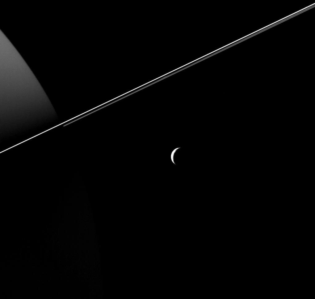 Tethys, dwarfed by the scale of Saturn and its rings, appears as an elegant crescent in this Cassini image