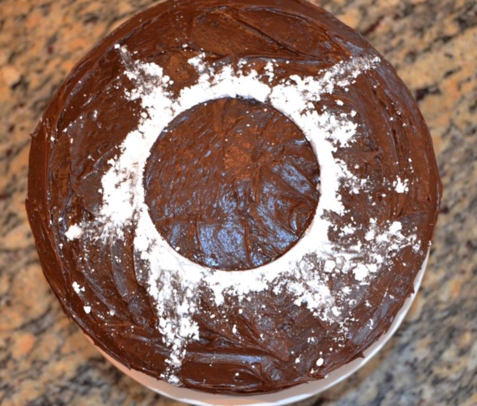 An image of a chocolate cake on a pedestal, with powdered sugar on top, representing the Sun's corona during a total solar eclipse.