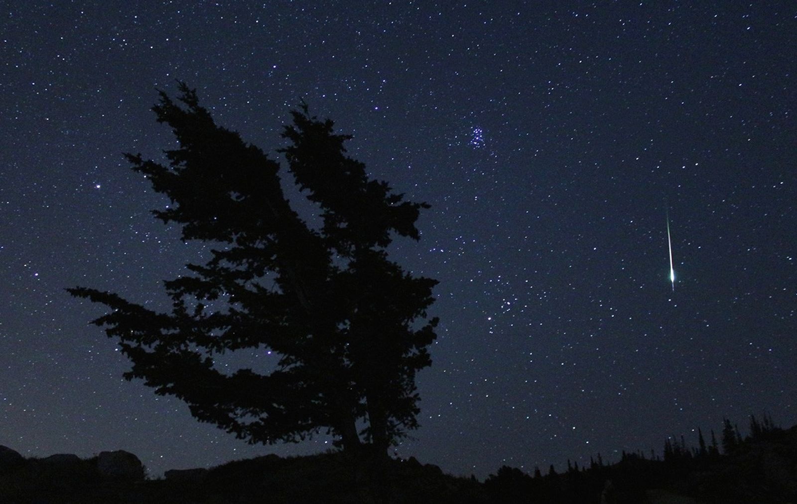 Meteor falling against dark, starry sky.