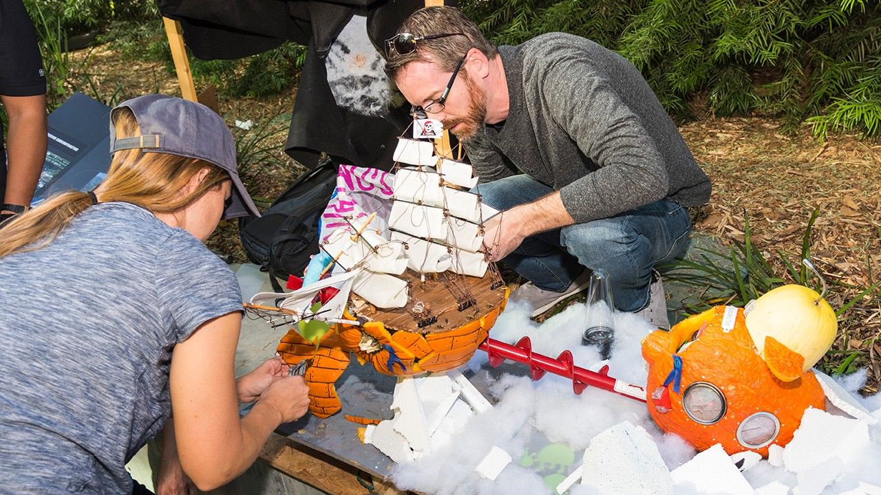 Man and woman working on elaborate pumpkin carvings