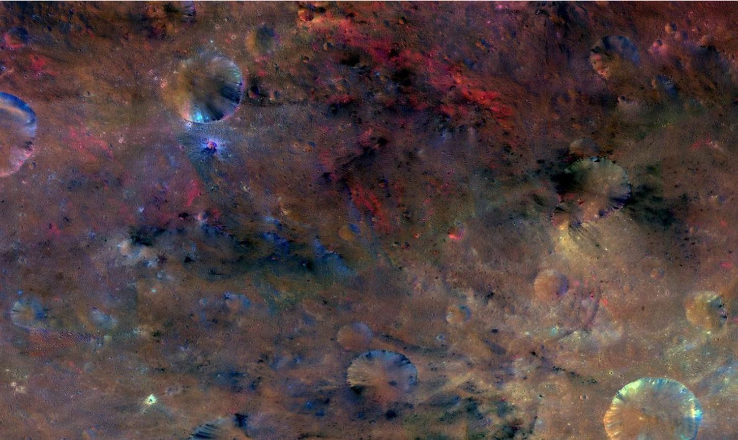 Color enhanced view of rugged, cratered asteroid surface.