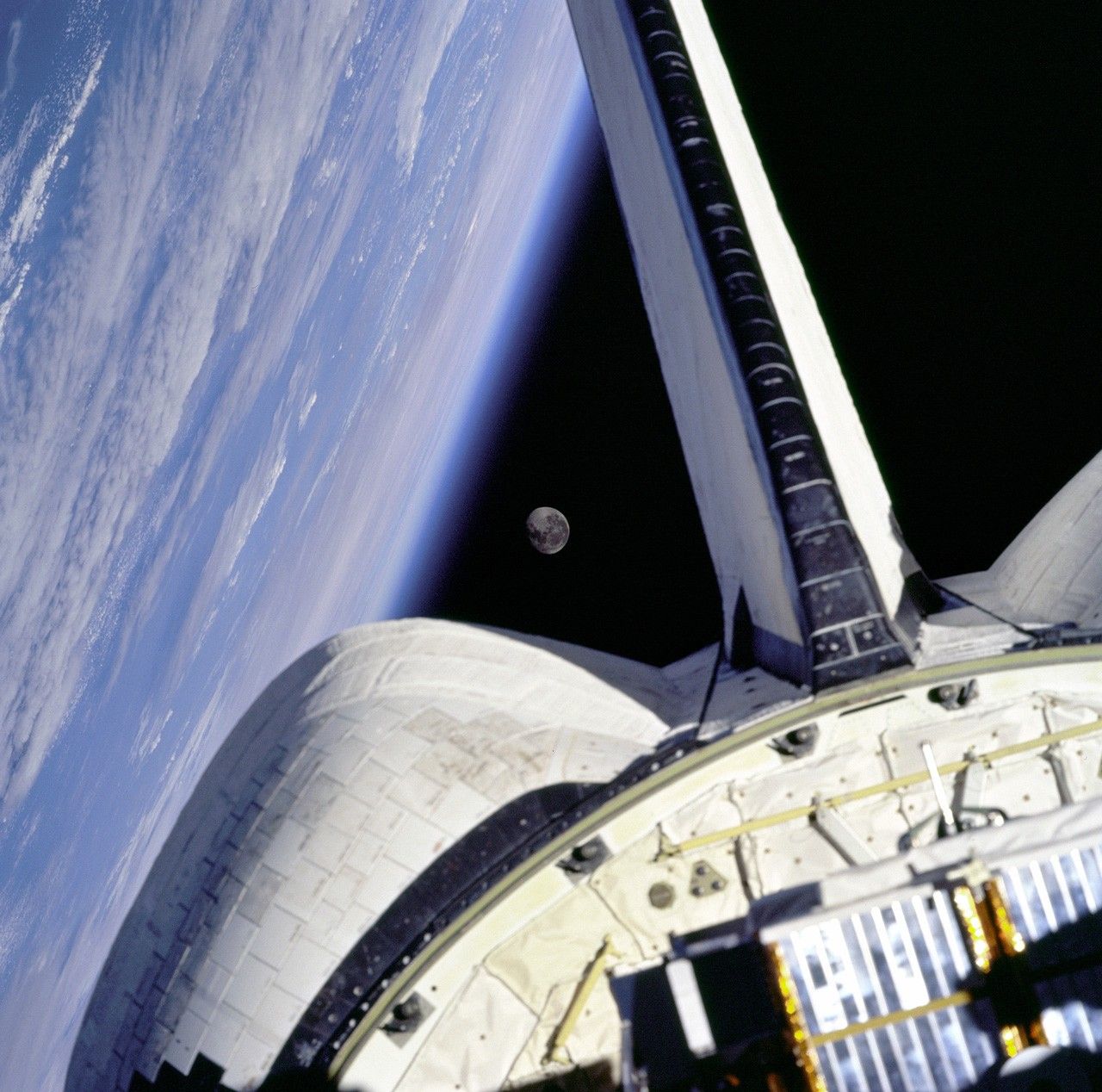 Moon over Earth with the Space Shuttle in the foreground.