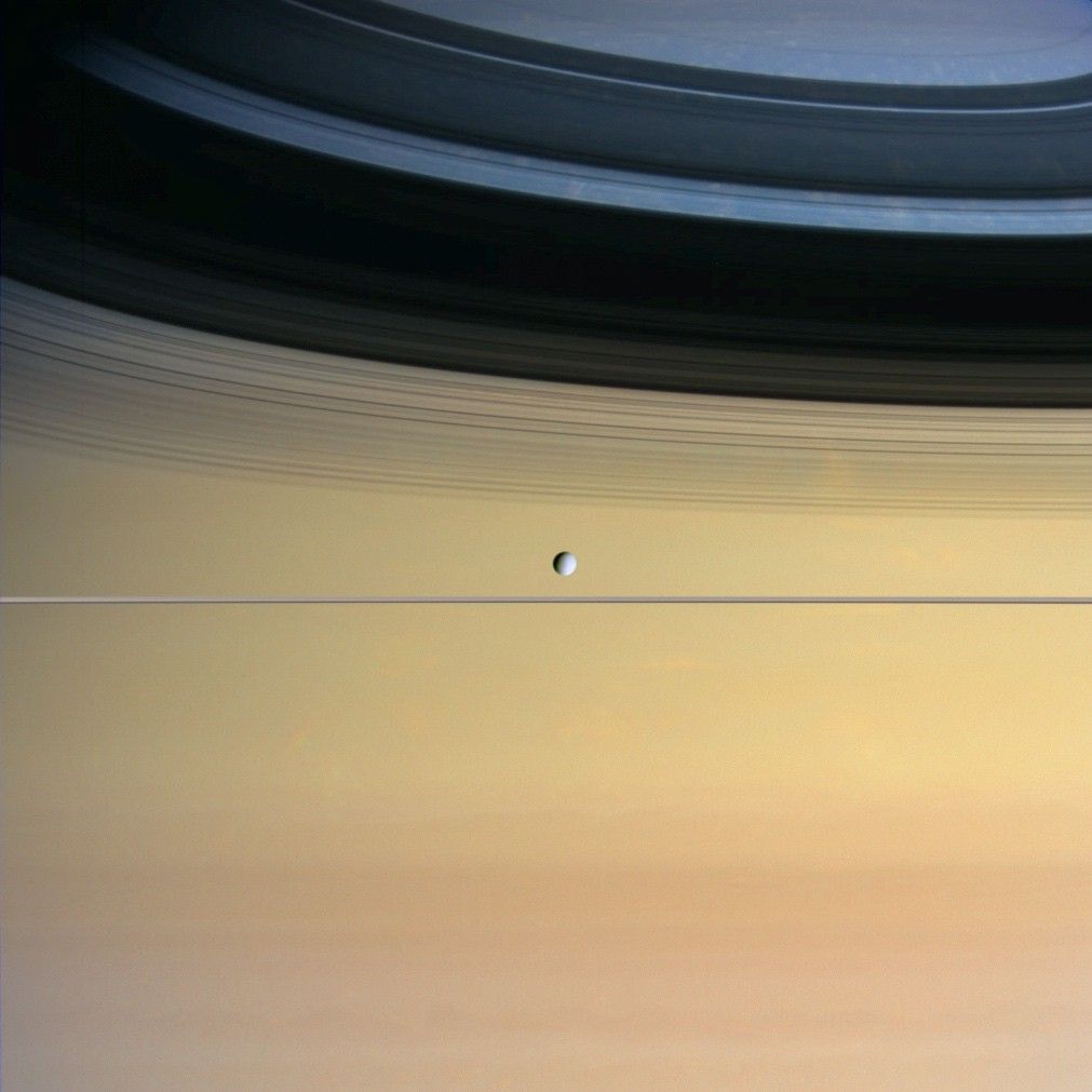moon floating before immense face of Saturn